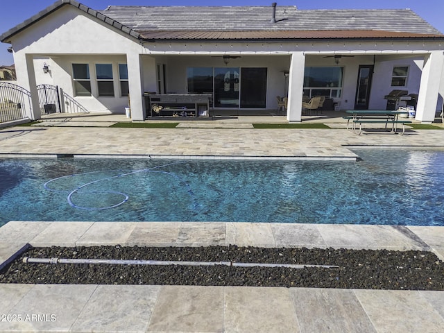 rear view of house featuring a patio, a gate, an outdoor pool, ceiling fan, and stucco siding