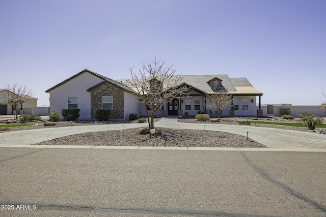 view of front of home with decorative driveway, stone siding, and stucco siding