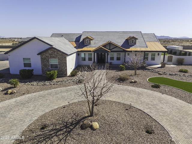 view of front of property featuring decorative driveway, metal roof, fence, and stucco siding