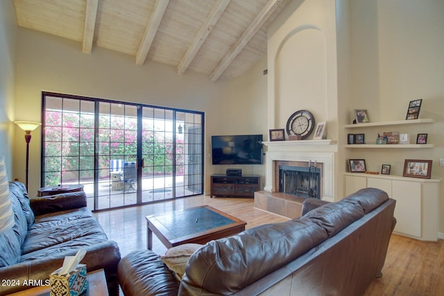 living room featuring wooden ceiling, high vaulted ceiling, a tile fireplace, light hardwood / wood-style flooring, and beam ceiling