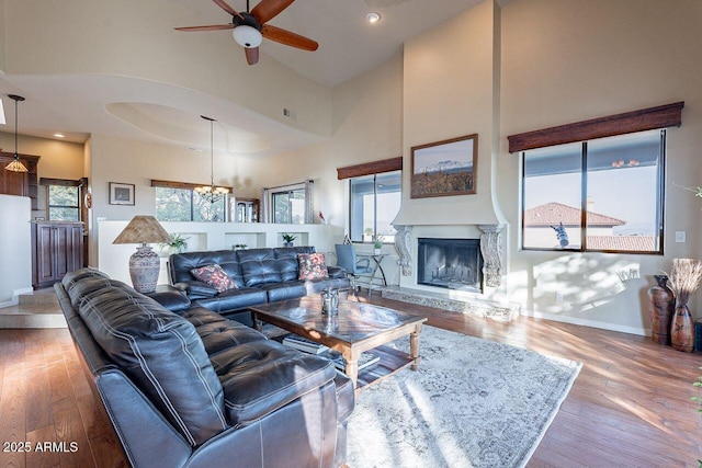 living room featuring hardwood / wood-style flooring, ceiling fan, and a high ceiling