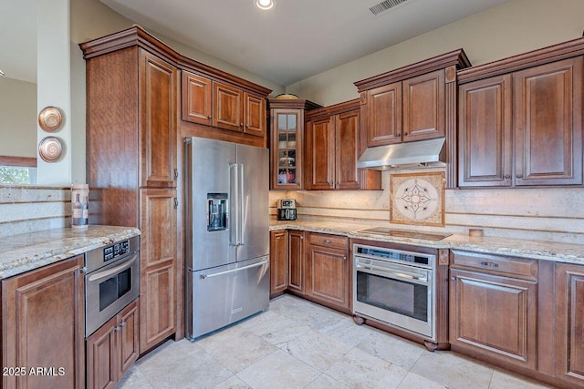 kitchen with stainless steel appliances, light stone countertops, and decorative backsplash