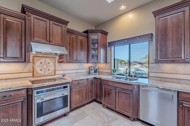 kitchen featuring stainless steel appliances, light stone countertops, sink, and backsplash