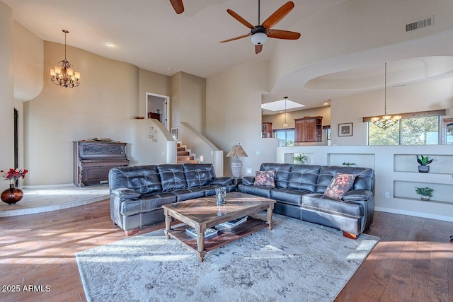 living room featuring ceiling fan with notable chandelier, a towering ceiling, and hardwood / wood-style floors