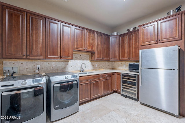 washroom featuring wine cooler, sink, and washing machine and dryer