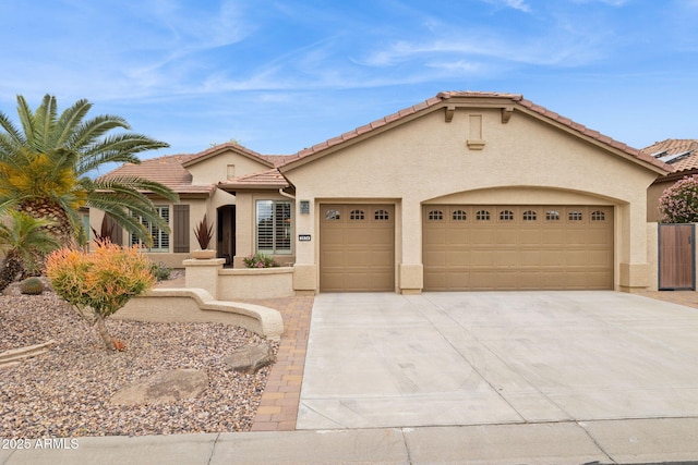 mediterranean / spanish house featuring stucco siding, an attached garage, a tile roof, and driveway