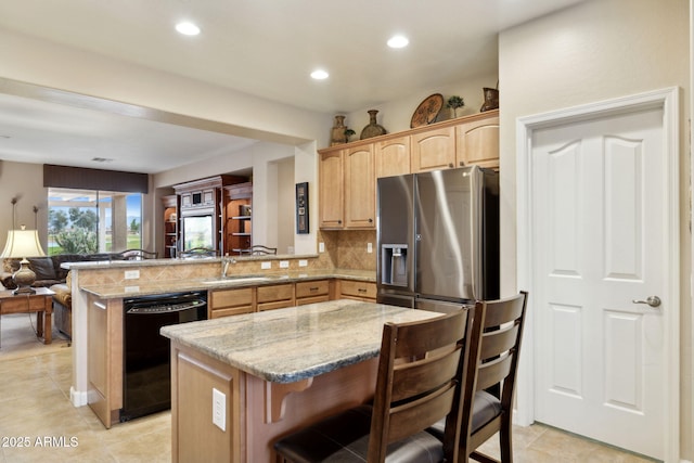 kitchen featuring light brown cabinets, backsplash, black dishwasher, open floor plan, and a peninsula