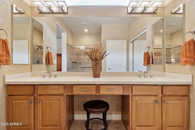 bathroom featuring double vanity, visible vents, tiled shower, and a sink