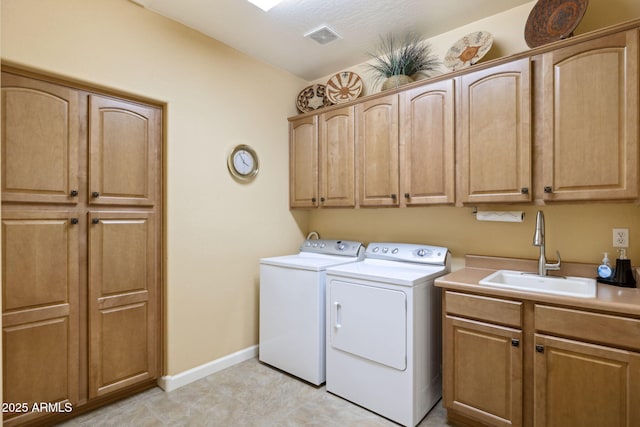 washroom featuring visible vents, washer and dryer, a sink, cabinet space, and baseboards