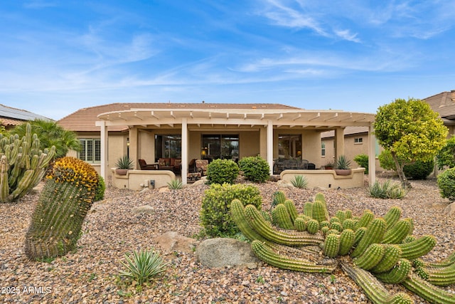 rear view of property featuring stucco siding, a pergola, and a patio area