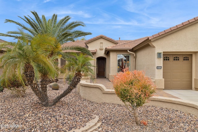 view of front of home featuring stucco siding, driveway, a tile roof, and a garage