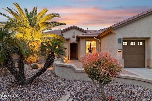 view of front of property with a tiled roof, stucco siding, an attached garage, and concrete driveway