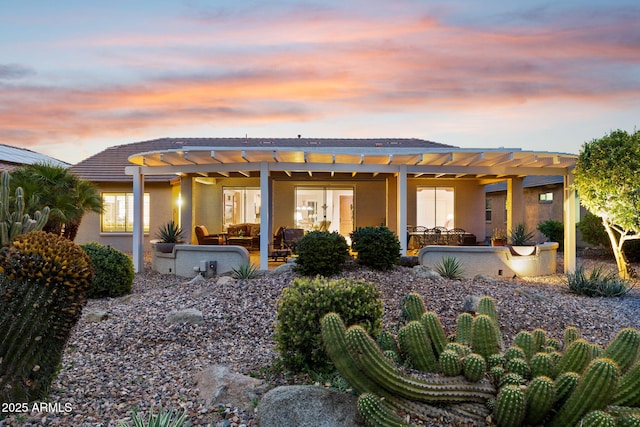 rear view of house featuring stucco siding, a tile roof, a pergola, a patio, and outdoor lounge area