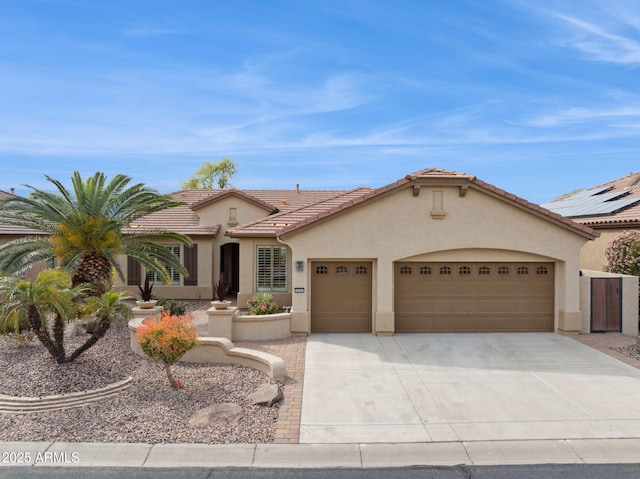 mediterranean / spanish-style home with concrete driveway, a tiled roof, an attached garage, and stucco siding