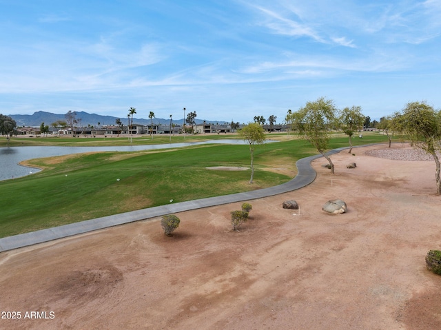 view of property's community featuring a yard, a water and mountain view, and golf course view