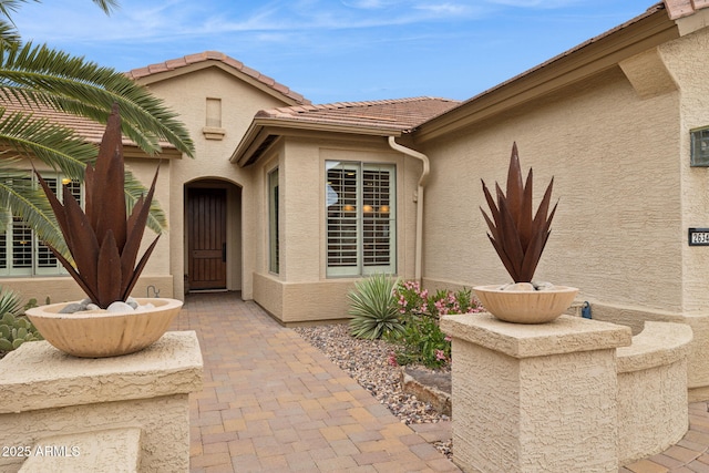 property entrance with a tiled roof and stucco siding