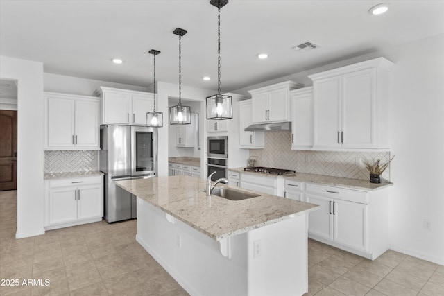 kitchen featuring decorative backsplash, appliances with stainless steel finishes, a center island with sink, and white cabinets