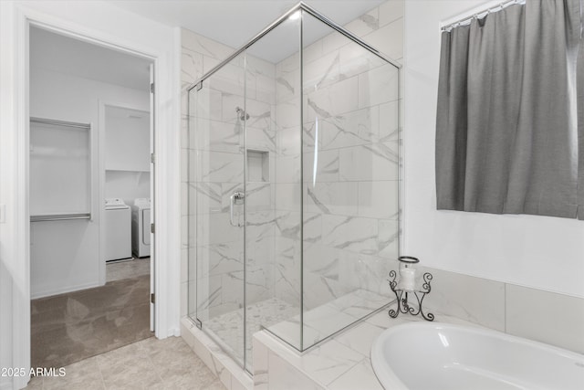 bathroom featuring independent washer and dryer and shower with separate bathtub