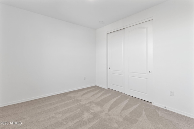 unfurnished bedroom with a closet and light carpet