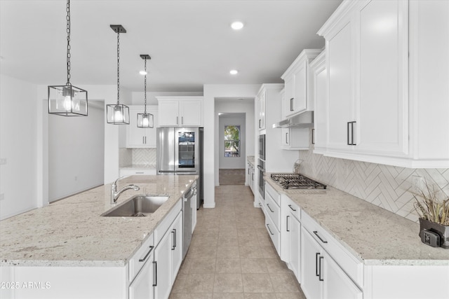 kitchen with appliances with stainless steel finishes, decorative light fixtures, tasteful backsplash, an island with sink, and sink