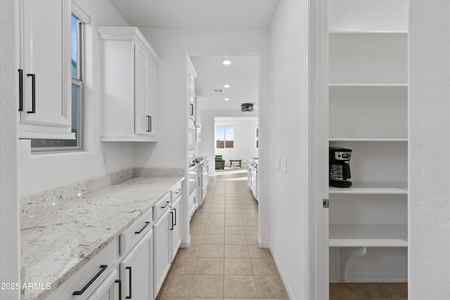 kitchen with white cabinetry, light stone countertops, and light tile patterned floors