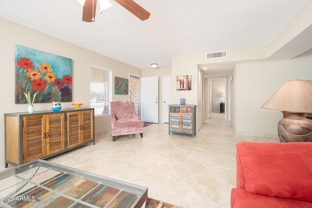 interior space featuring a ceiling fan, visible vents, and a textured ceiling