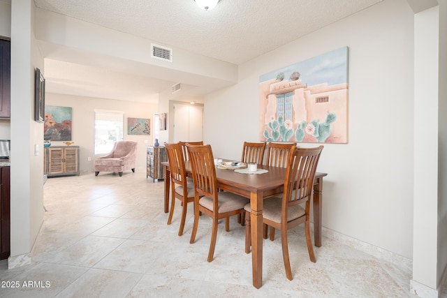 dining area with visible vents, a textured ceiling, baseboards, and light tile patterned floors