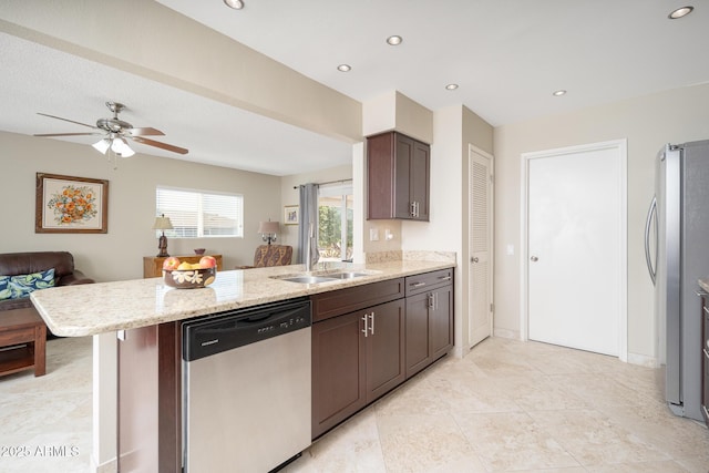 kitchen featuring stainless steel appliances, open floor plan, dark brown cabinetry, a sink, and a peninsula