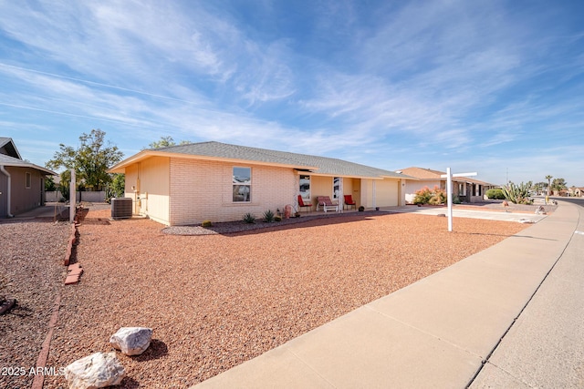 single story home with a garage, brick siding, driveway, and central air condition unit