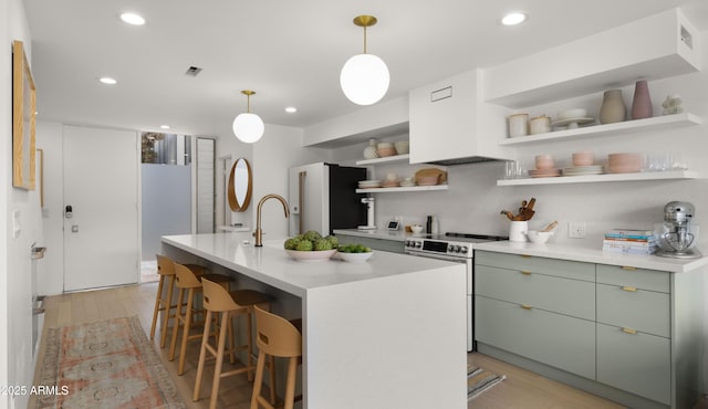 kitchen with open shelves, light wood-type flooring, green cabinetry, stainless steel electric stove, and fridge with ice dispenser