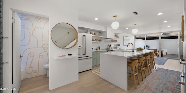 kitchen featuring a sink, light countertops, white fridge with ice dispenser, and light wood-type flooring