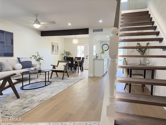 living room with ceiling fan with notable chandelier and light hardwood / wood-style flooring