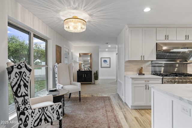 kitchen featuring decorative backsplash, an inviting chandelier, white cabinets, and light wood finished floors