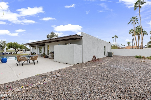 rear view of house featuring a patio, fence, an outdoor pool, stucco siding, and central air condition unit