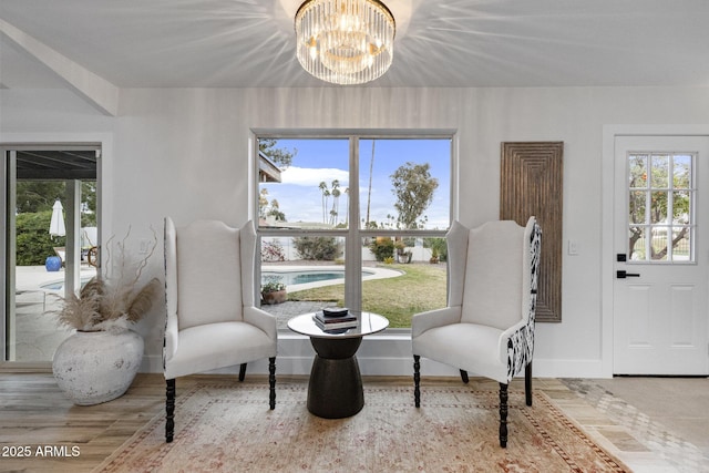 sitting room featuring baseboards, wood finished floors, a healthy amount of sunlight, and a chandelier