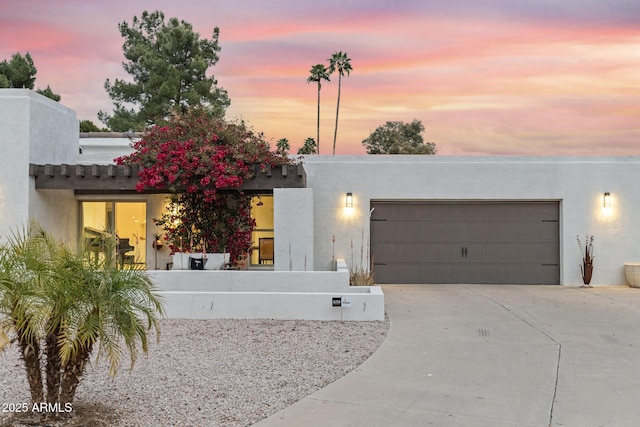 adobe home with stucco siding, concrete driveway, and a garage