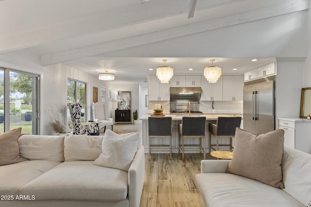 living area with recessed lighting, vaulted ceiling with beams, and light wood finished floors