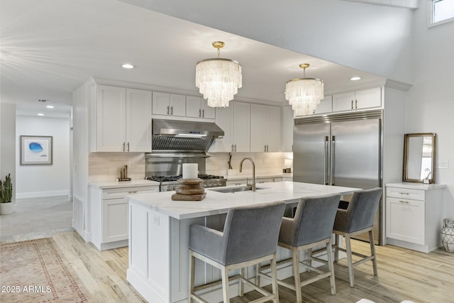 kitchen featuring stove, tasteful backsplash, under cabinet range hood, and a chandelier