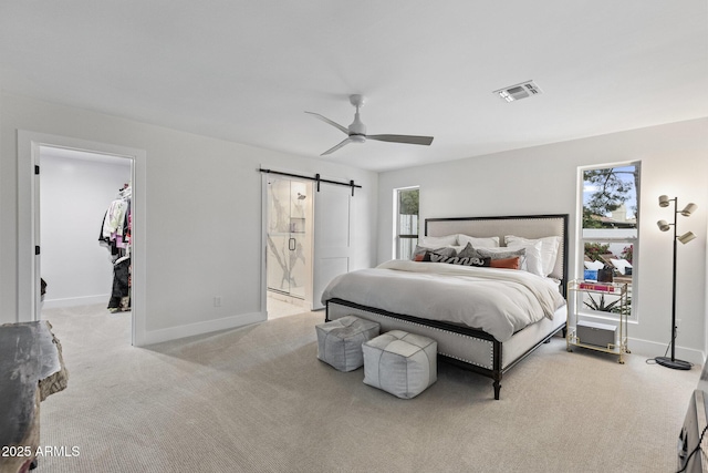 carpeted bedroom featuring visible vents, a barn door, connected bathroom, baseboards, and a spacious closet