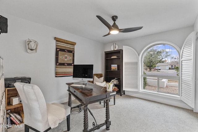 carpeted office with a ceiling fan