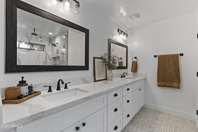 full bath with a sink, a marble finish shower, baseboards, and double vanity