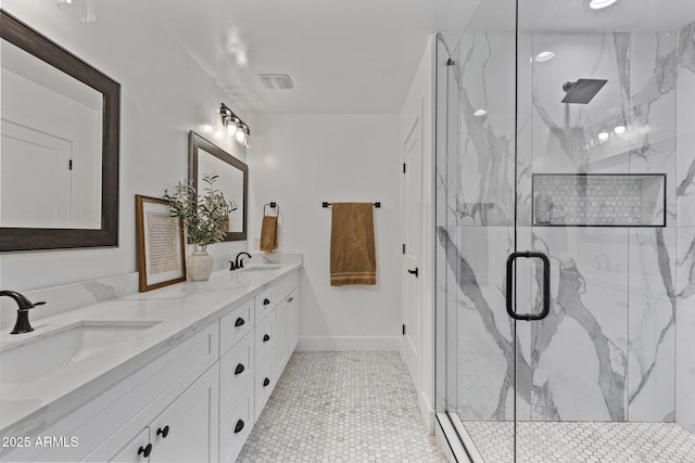 full bath with a sink, a marble finish shower, baseboards, and double vanity