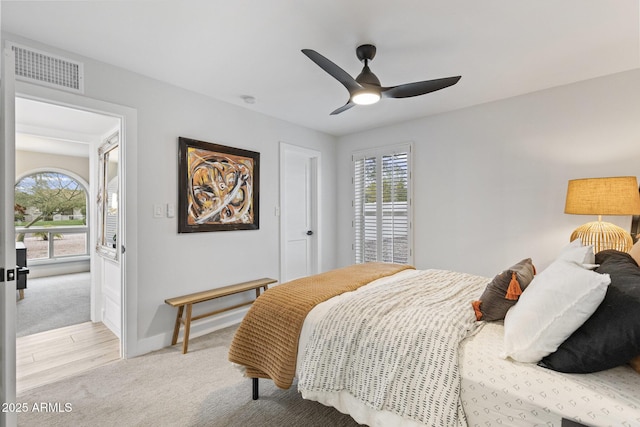 bedroom featuring ceiling fan, light colored carpet, visible vents, and baseboards