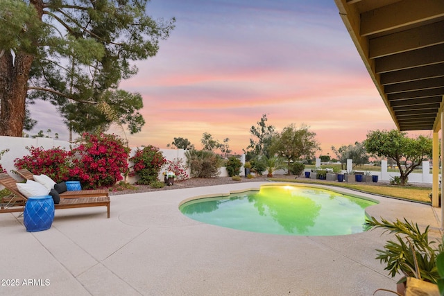 pool at dusk with a patio and fence