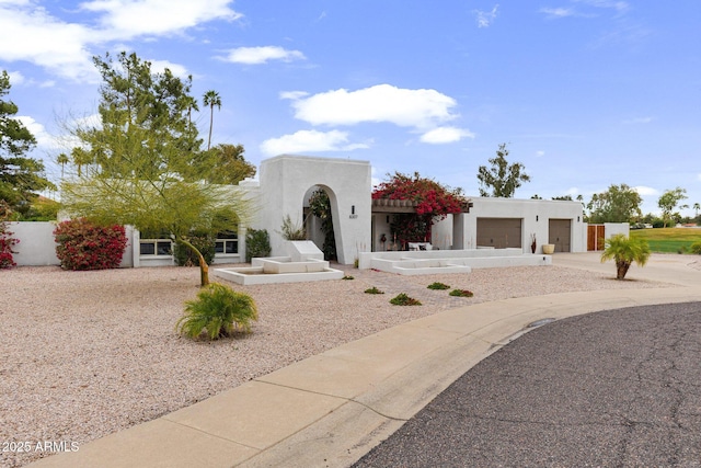 adobe home with stucco siding, a garage, driveway, and fence