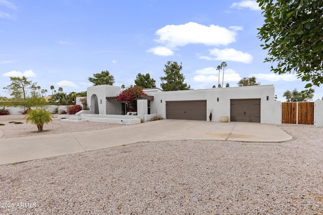 southwest-style home featuring stucco siding, an attached garage, driveway, and fence