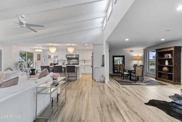 living room featuring visible vents, light wood-type flooring, lofted ceiling with beams, recessed lighting, and a ceiling fan