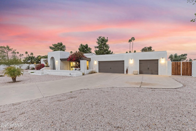 southwest-style home with concrete driveway, fence, a garage, and stucco siding