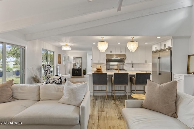 living room with lofted ceiling with beams, light wood-type flooring, and recessed lighting