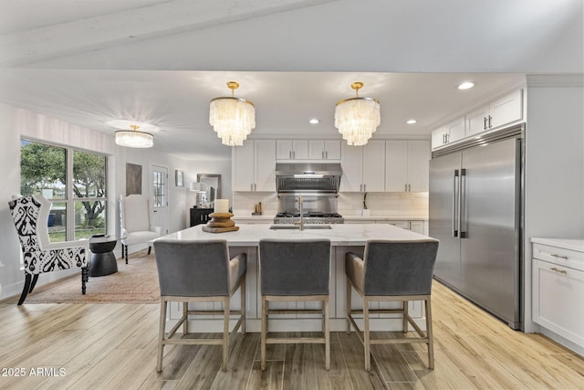 kitchen with a notable chandelier, light countertops, and built in fridge